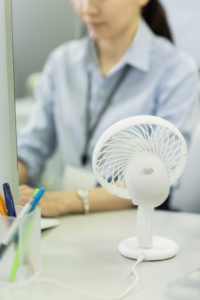 A businesswoman works by a small fan